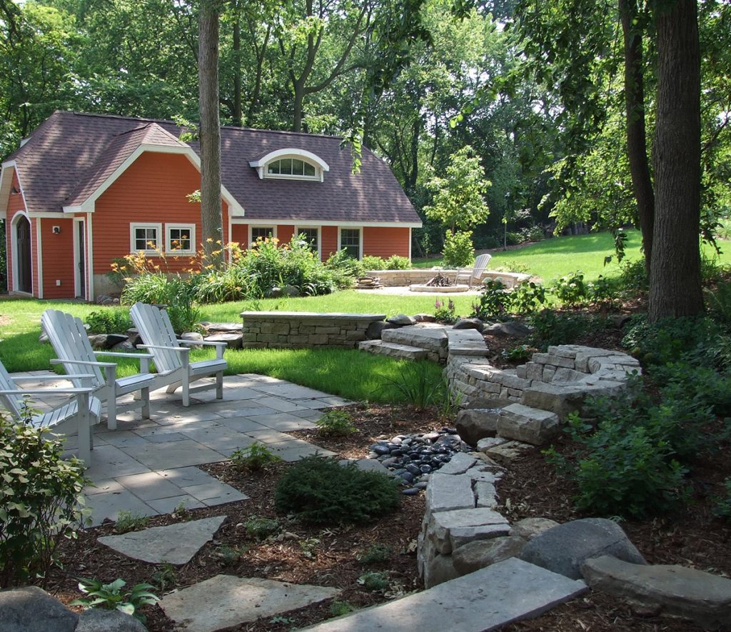 Residential backyard with patio seating, green landscape, and red barn